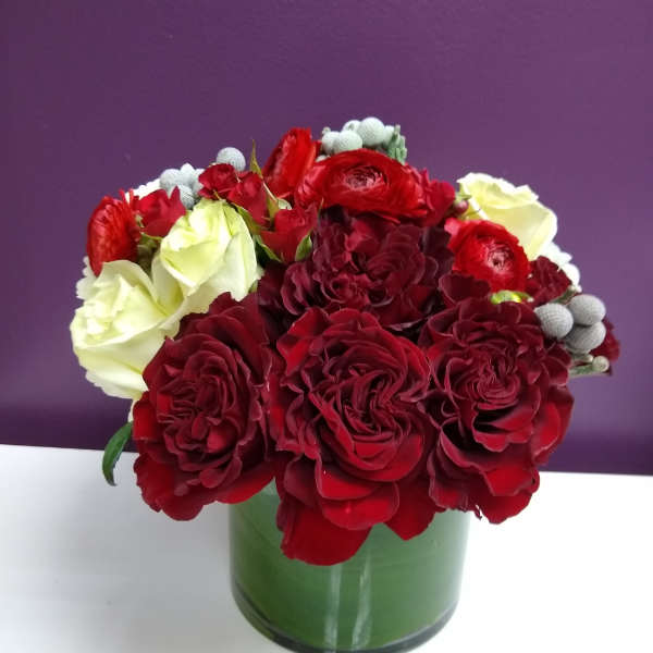 Red and white rose bouquet in a green glass vase