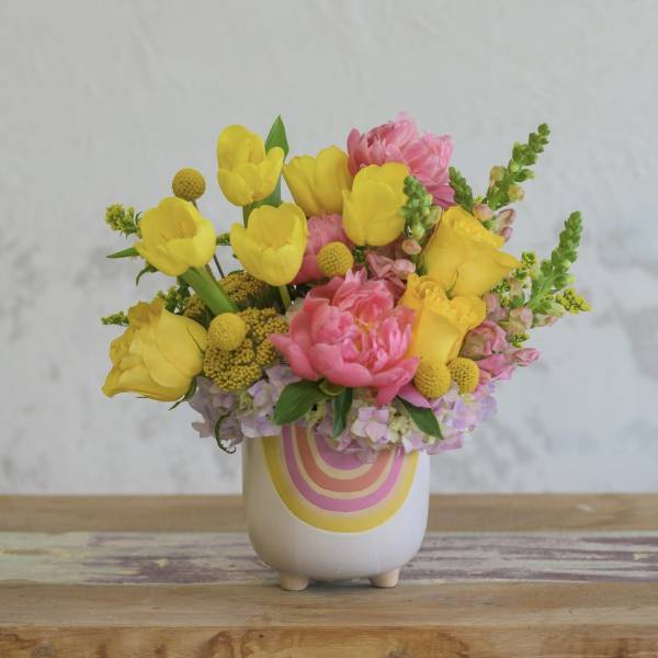 Yellow tulips and pink flowers in a white ceramic vase