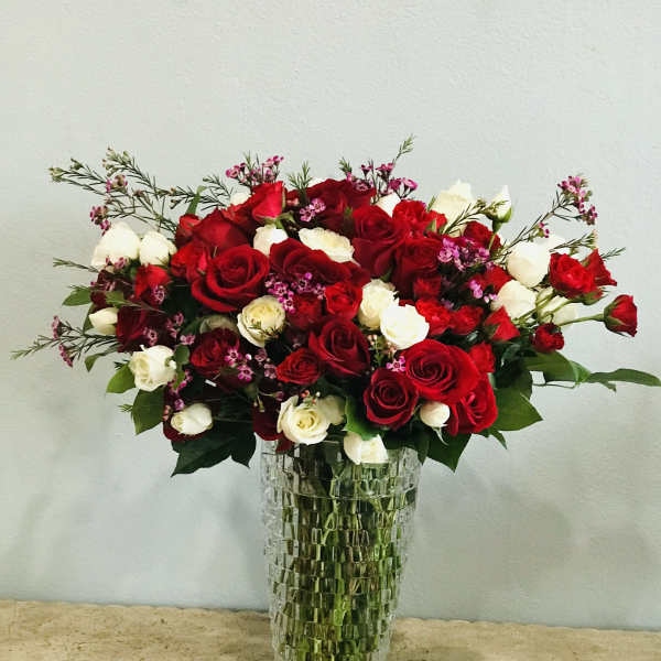 Red and white roses arranged in a tall glass vase