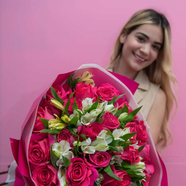 Woman holding a bouquet of pink roses and white flowers wrapped in pink paper