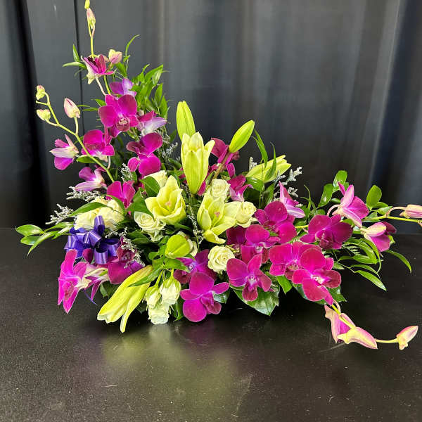 Magenta orchids and pale lilies arranged low on a black surface