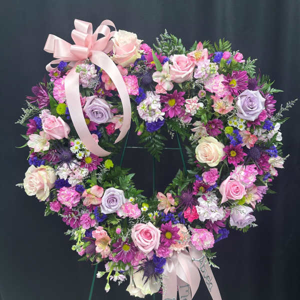 Heart-shaped floral wreath with pink and purple flowers and a ribbon bow