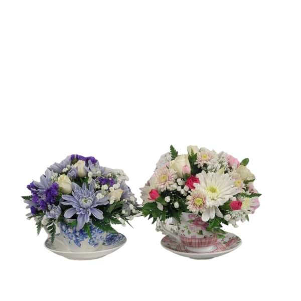 Two mixed flower arrangements in teacups on saucers