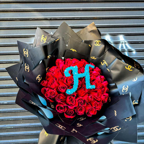 Large bouquet of red roses with blue monogram, wrapped in black logo paper