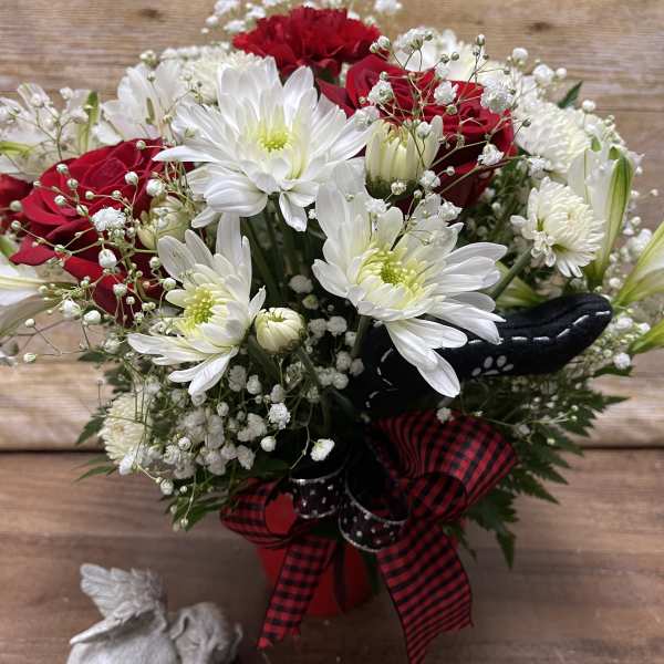 Bouquet of red roses and white daisies in a red vase with a plaid ribbon
