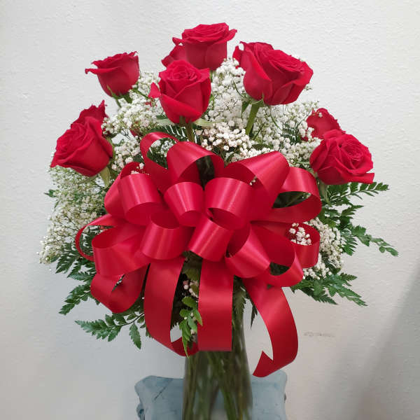 Bouquet of red roses with baby's breath in a glass vase and red ribbon