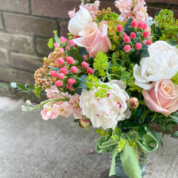 Bouquet of pale pink roses, white peonies, and pink blossoms in a vase