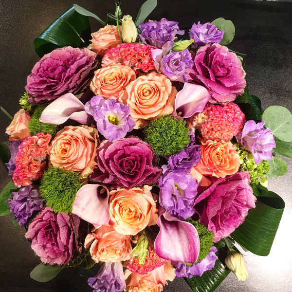 Round bouquet of peach roses, purple blooms, and pink calla lilies
