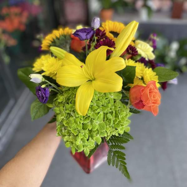 Bouquet with yellow lily, green hydrangea, and mixed purple and orange flowers