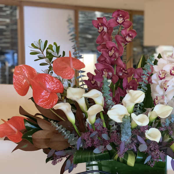 Tall arrangement with orchids, calla lilies, and anthuriums in a vase