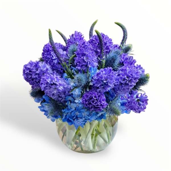 Blue and purple flower arrangement in a clear glass vase