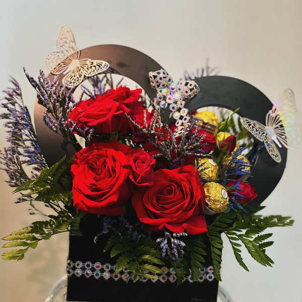 Red roses in a black gift box with butterfly decorations