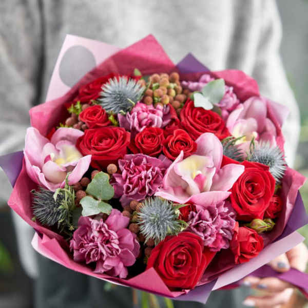 Bouquet of red roses and pink orchids wrapped in pink paper