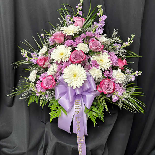 Pink and white floral spray with a lavender ribbon on black fabric