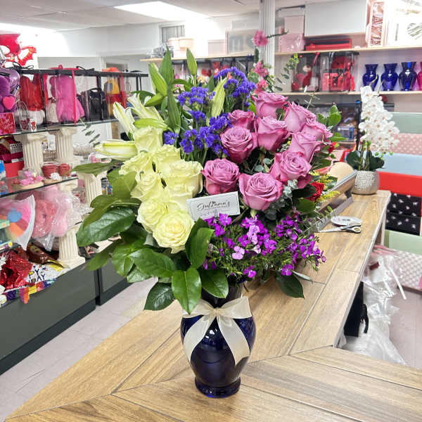 Mixed bouquet of pink and white roses with lilies in a blue vase