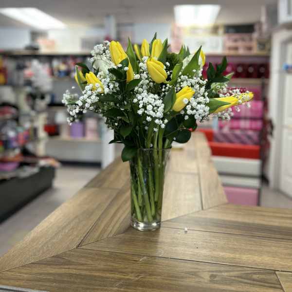 Yellow tulips and white baby's breath in a clear glass vase