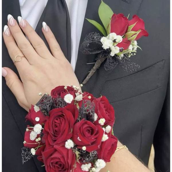 Red rose boutonniere and wrist corsage on a black suit