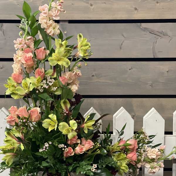Tall floral arrangement with pink roses and yellow alstroemeria in a white container