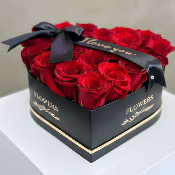 Red roses arranged in a black heart-shaped box with a ribbon