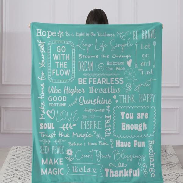 Person holding a teal blanket with white inspirational phrases