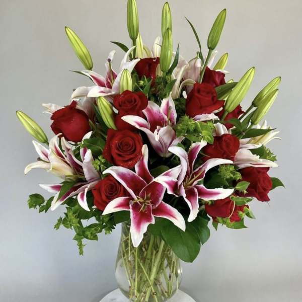 Bouquet of red roses and pink-white lilies in a clear glass vase