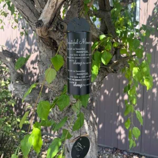 Black memorial wind chime hanging from a tree branch