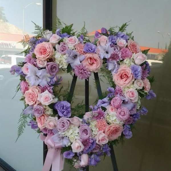 Heart-shaped floral wreath with pink and lavender roses on an easel
