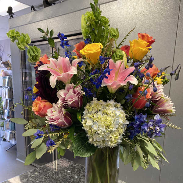 Mixed bouquet of roses, lilies, and hydrangea in a glass vase