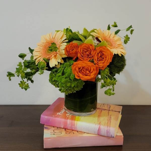 Orange roses and pale peach gerbera daisies in a glass vase