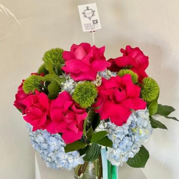 Bouquet of hot pink roses and blue hydrangeas in a glass vase