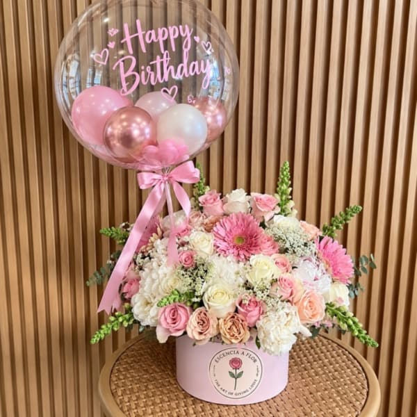Pink birthday balloon above a pastel rose and gerbera arrangement in a pink box