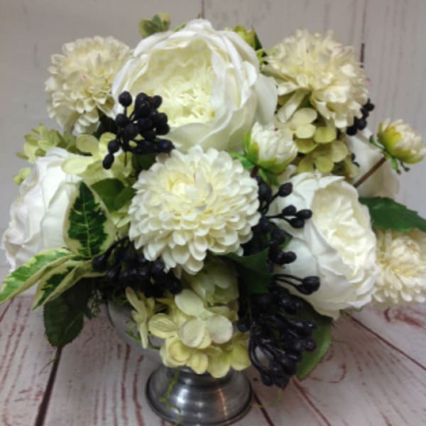 Low arrangement of white roses and mums with dark berries in a silver pedestal bowl
