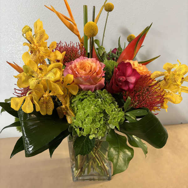 Tropical bouquet in a clear glass vase with yellow orchids and orange-red blooms