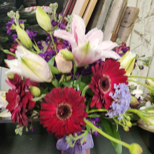 Bouquet of lilies and red gerbera daisies in a small vase