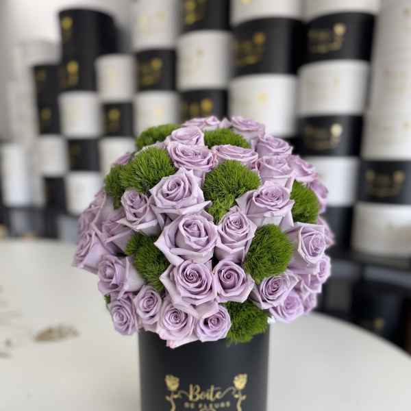 Lavender roses arranged with green pom-pom accents in a black hat box