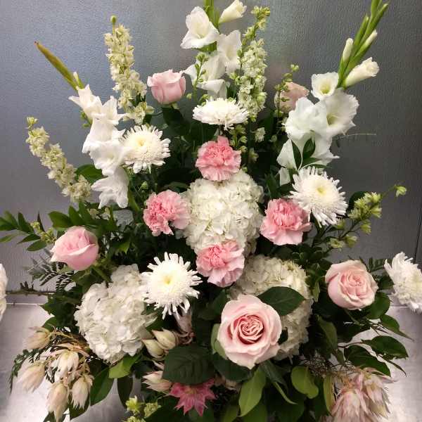 Pink roses, white hydrangeas, and white daisies in a tall arrangement
