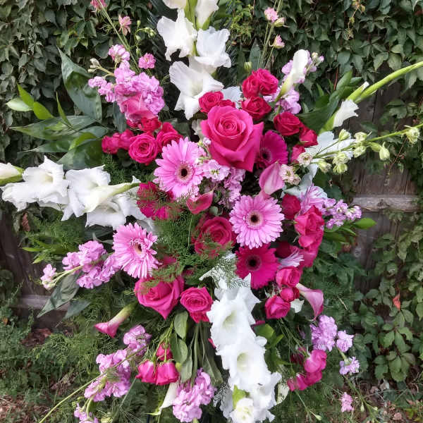 Large standing floral spray with pink roses, gerbera daisies, and white gladiolus