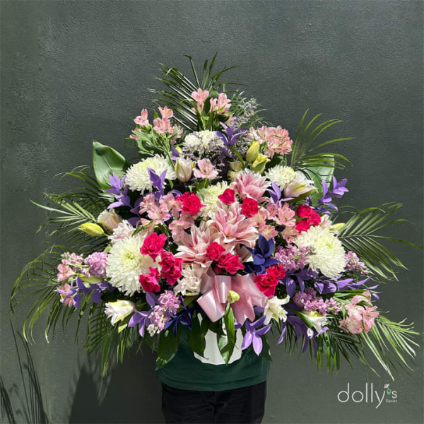 Large mixed bouquet in a white container with pink and purple flowers