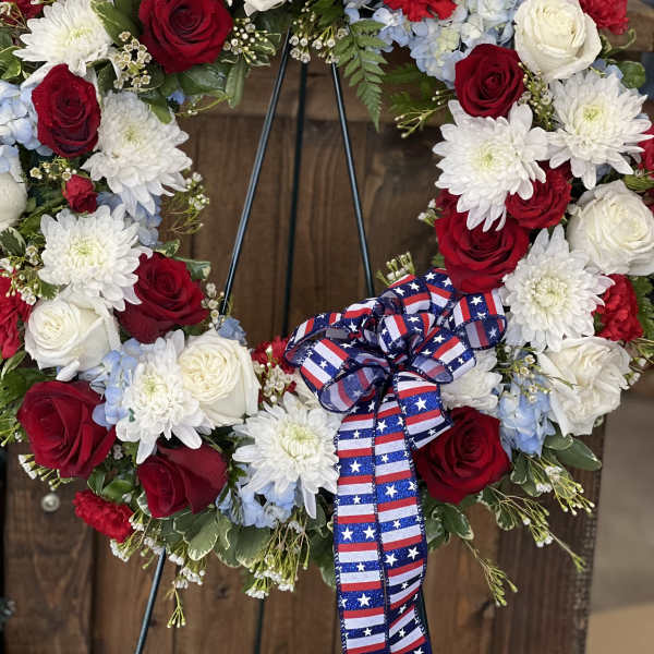 Red, white, and blue floral wreath with a patriotic ribbon bow