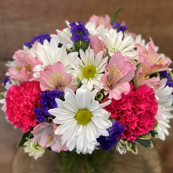 Bouquet of pink and white flowers with purple accents in a glass vase