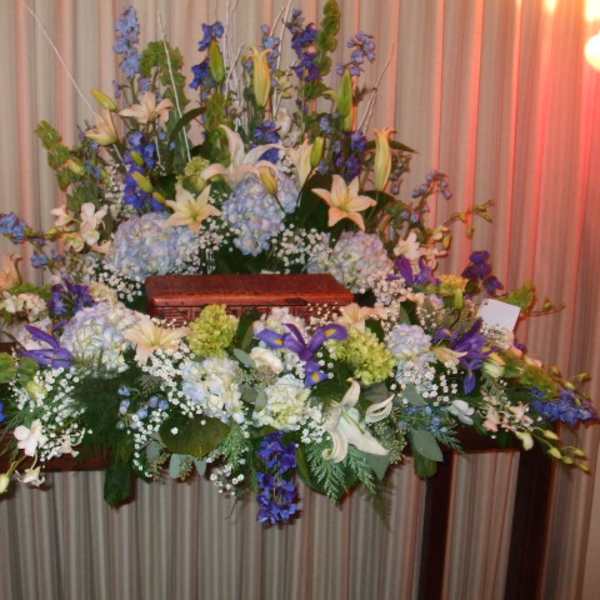 Large floral casket spray with white lilies and blue flowers
