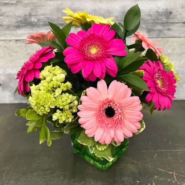 Bouquet of pink, peach, and yellow gerbera daisies in a green vase