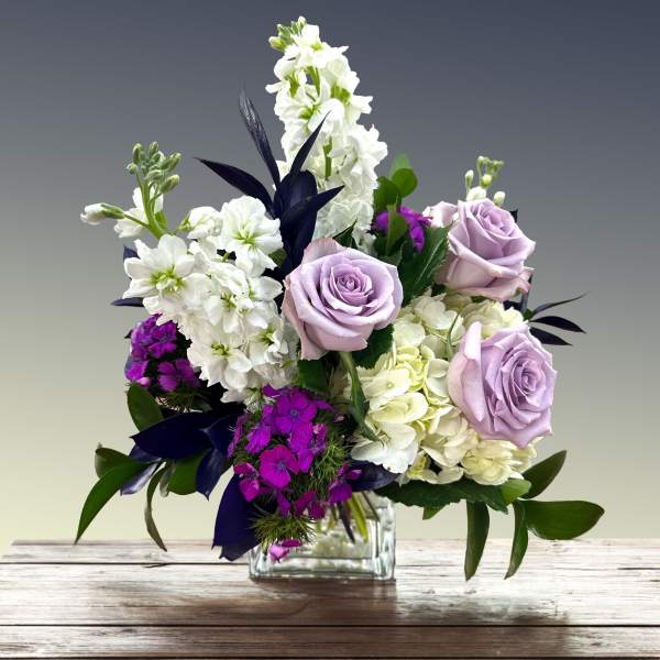 Lavender roses and white flowers in a clear glass vase