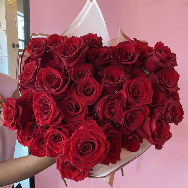 Large bouquet of red roses wrapped in white and tan paper