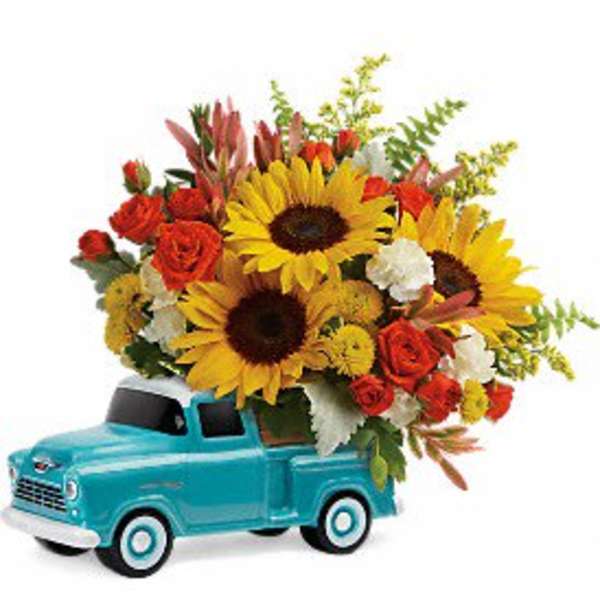 Sunflowers and red roses arranged in a turquoise toy truck