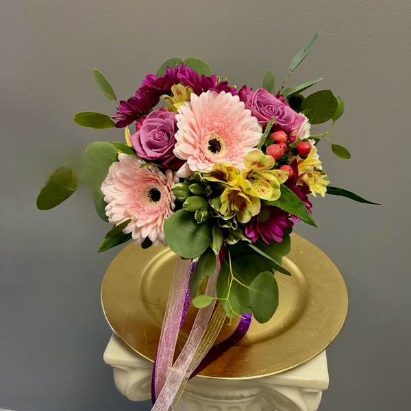 Bouquet of pink gerbera daisies, purple roses, and yellow alstroemeria