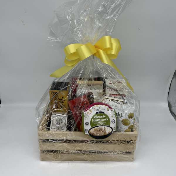 Gift basket of assorted snacks wrapped in clear cellophane with a yellow bow
