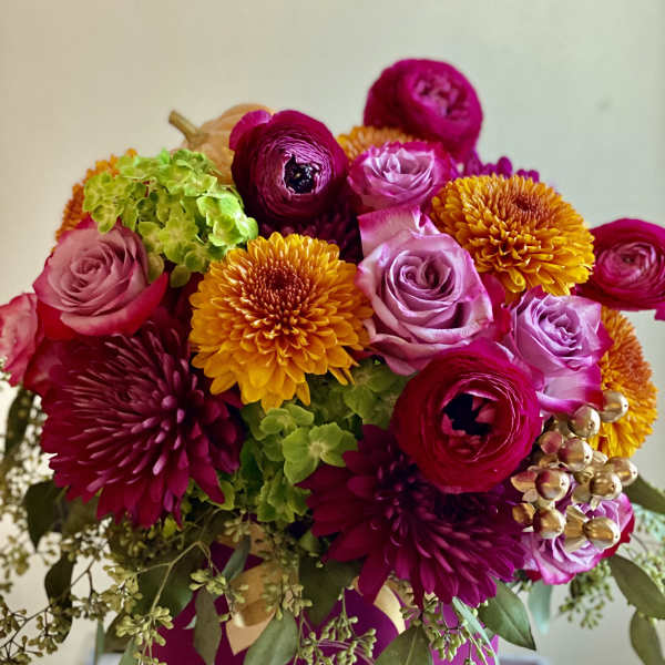 Bright mixed bouquet with pink, purple, and yellow blooms in a magenta box