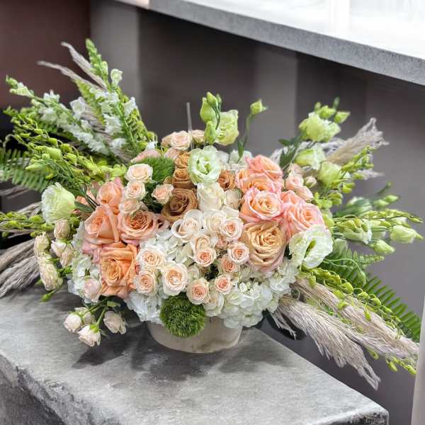 Peach and white rose arrangement in a low round vase