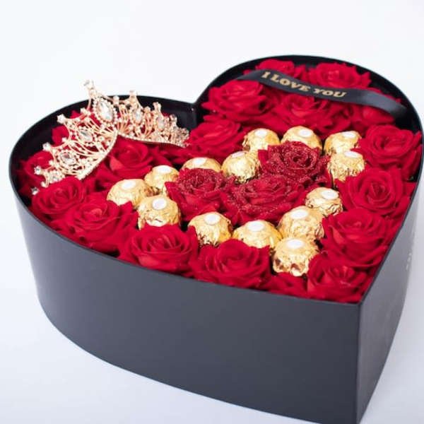 Heart-shaped box of red roses with gold chocolates and a tiara